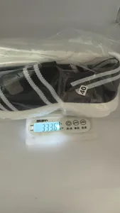 Detailansicht des Gewichts einer schwarz-weiß gestreiften Strick-Keilsandalette auf der Waage.