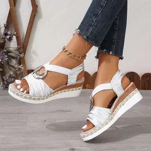 Close-up detail of women's silver wedge sandals featuring a metal buckle and rope trim