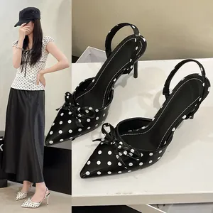 Vista detallada de tacones slingback con lunares negros de estilo francés y lazo.
