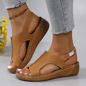Detail of stylish brown wedge sandals featuring cut-out upper and white stitching.