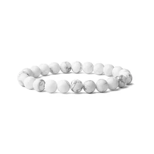 Gros plan d'un bracelet en perles de turquoise blanche de 8mm aux motifs marbrés gris.
