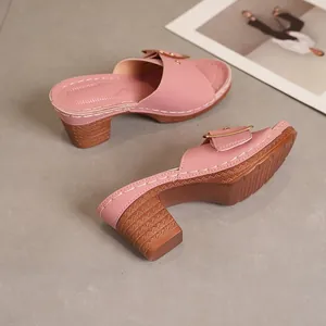 Detailed view of pink high-heeled mule sandals with gold buckle and elegant block heel.