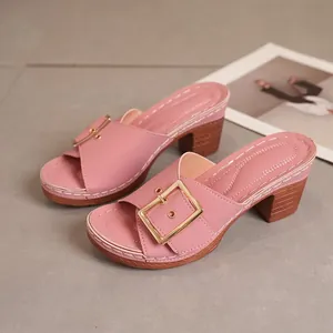 Close-up of stylish pink high-heel mule sandals with elegant gold metal buckle detail.