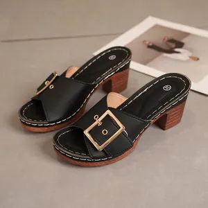 Elegant black mule sandals featuring a gold buckle and chunky wood-textured heel