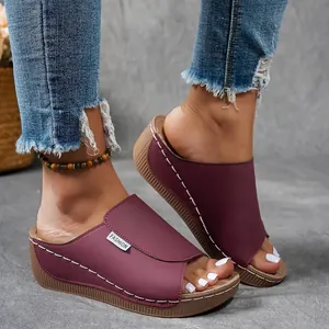 Close-up of burgundy wedge platform sandals with peep-toe and white stitching details