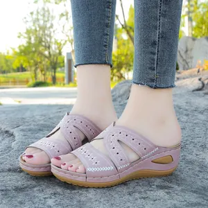 Vista puesta de sandalias con cuña bordadas en violeta con motivo floral y punta abierta