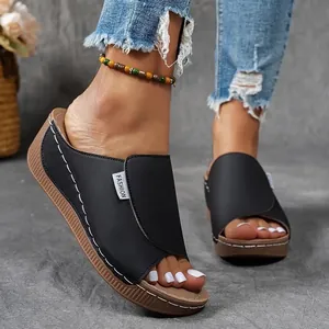 Close-up of black platform peep-toe sandals with white stitching and bead anklet decoration.