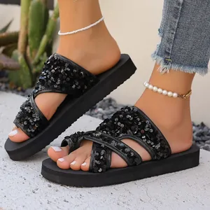 Détail de sandales à plateforme à paillettes noires portées par une femme dehors