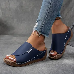 Navy blue wedge sandals on model featuring white decorative stitching and peep-toe