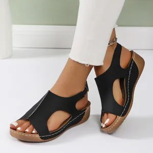 Close-up of black hollow-out wedge sandals for women with white stitching.