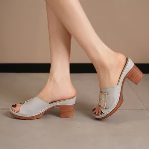 Detailed side view of grey high-heeled mule sandals with gold buckle and wood block heel