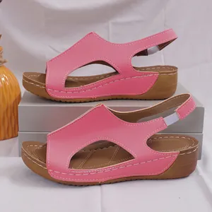 Close-up detail of pink wedge sandals featuring cut-out leather and contrast stitching