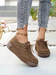 Detailansicht stilvoller brauner Plateau-Slipper für Damen aus Canvas mit Schnürdesign