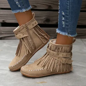 Primer plano de botines de ante con flecos, correas con remaches y suela plana