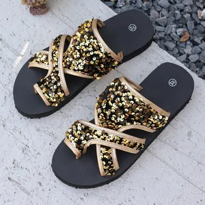 Détail de sandales de plage avec brides croisées ornées de paillettes dorées scintillantes.