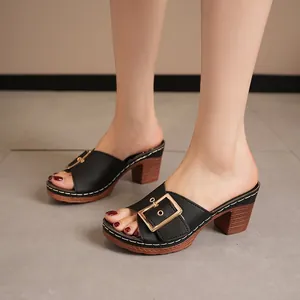 Stylish black high-heel mule sandals with gold buckle on model feet