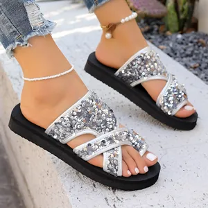 Gros plan de sandales à paillettes argentées pour femmes avec semelles noires souples.
