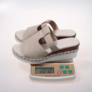 Detail view of lightweight beige wedge sandals being weighed on a precise digital scale