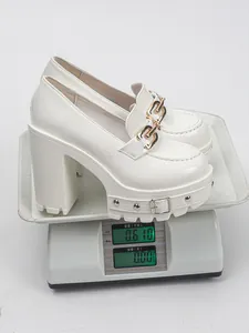 Weiße Punk-Gothic-Plateau-Loafer mit klobigem Absatz auf einer digitalen Waage gewogen