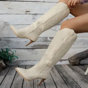 Détail de bottes de cowboy occidentales brodées crème à talons hauts pour femmes.