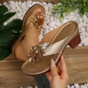 Elegant metallic gold wedge flip-flop sandals featuring a large decorative flower detail