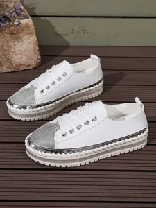Stylish white platform sneakers with sparkly silver rhinestone toe cap on wooden deck