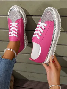 Close-up of stylish pink platform sneakers with sparkling rhinestone toe details.