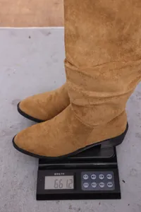 Detailweergave van camelkleurige suède plooilaarzen die 661,2 g wegen op een digitale schaal