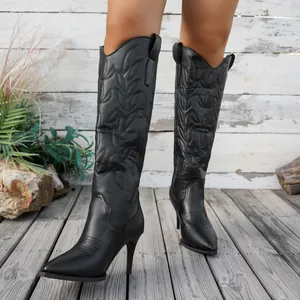 Vue détaillée des bottes de cowboy western noires brodées sur une terrasse en bois