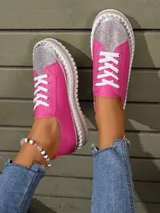 Detailed view of pink rhinestone platform loafers styled with blue jeans