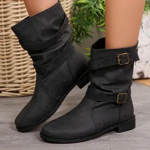 Zoom sur des bottines noires à mi-mollet avec brides à boucles et texture plissée.
