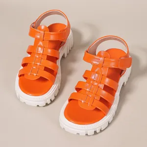 Close-up view of stylish orange Roman platform sandals featuring thick white lug soles.