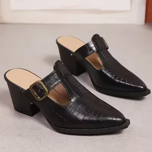 Vue de côté de mules noires à relief croco avec talon bloc et boucle dorée