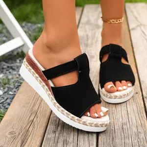 Close-up detail of black wedge platform sandals with espadrille trim on a wooden deck