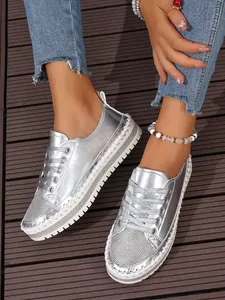 Close-up of silver metallic sneakers featuring rhinestone toe box and thick white platform soles