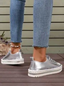 Close-up of women's silver metallic platform sneakers with rhinestone detailing on foot