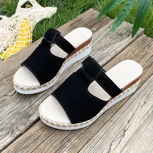 Stylish black wedge slide sandals with woven jute sole detail on rustic wood