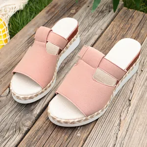 Detailed view of pink suede platform wedge sandals with woven trim on rustic wooden planks