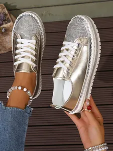 Detail view of gold rhinestone platform sneakers with metallic finish and white laces.