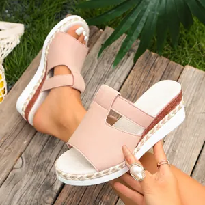 Close-up of pink suede wedge sandals with woven espadrille soles on a wooden deck.