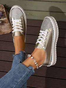 Close-up of stylish gold platform loafers with rhinestone accents and white laces.