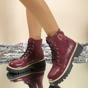 Gedetailleerd zijaanzicht van bordeauxrode platform Martin boots met reptieltextuur en gouden gesp