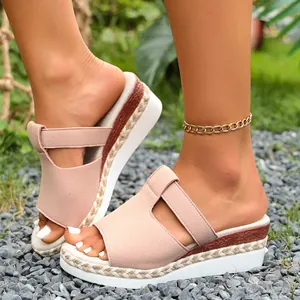 Close-up detail of pink suede-style wedge sandals featuring a woven platform sole on gravel