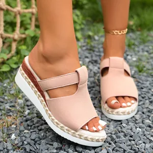Stylish pink wedge sandals with platform sole worn on outdoor gravel background.