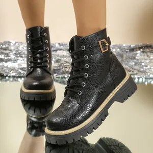 Detail van zwarte platform boots met krokodillentextuur en decoratieve gesp.