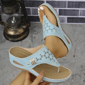 Primer plano de sandalias con cuña azul claro con diseño calado y hebilla metal