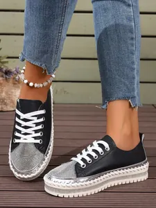 Close-up view of black platform sneakers featuring rhinestone toe and whipstitch sole detail