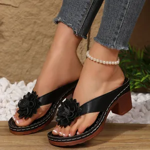 Close-up shot of stylish black flower-embellished block heel flip-flop sandals on feet