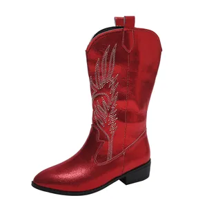 Close-up of metallic red cowboy boots featuring intricate white embroidery, pointed toe and block heel