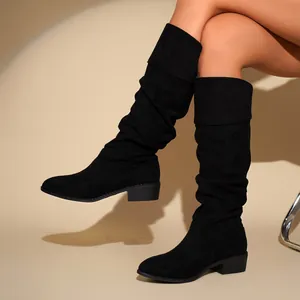 Close-up of women's black suede slouchy high boots with pleated texture and mid-block heel.